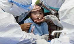 FILE | A child reacts to a throat swab during mass testing