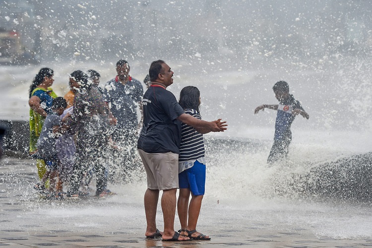 People enjoy a high tide at the Worli sea face in Mumbai on Saturday.