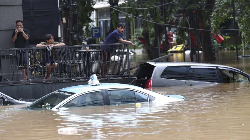People stand above at an office yard flooded following heavy rains in Jakarta, Indonesia. 
